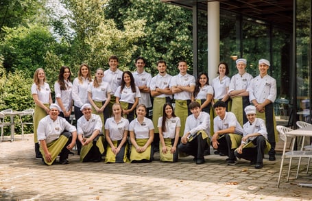 Gruppe von Menschen in Uniformen posiert draussen vor einem Gebäude.