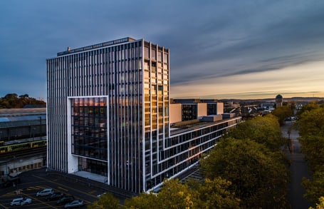 Hochhaus bei Sonnenuntergang mit Bäumen und Autos.