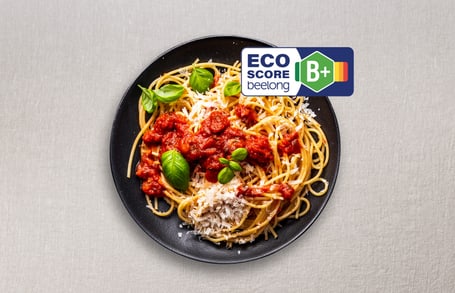 Teller mit Spaghetti und Tomatensosse, ECO-Score B+ Etikett.
