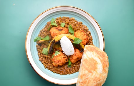 Linsengericht mit Brot auf grünem Hintergrund.
