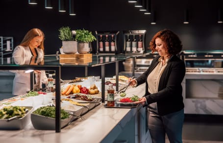 Zwei Frauen an einem Salatbuffet in einem Restaurant.