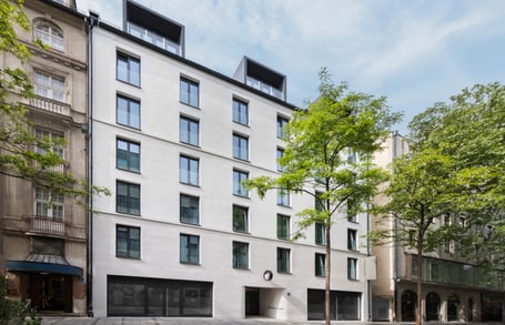 Moderne Mehrfamilienhausfassade mit Bäumen davor.
