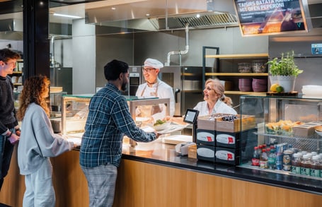 Menschen bestellen Essen an einem Imbissschalter.