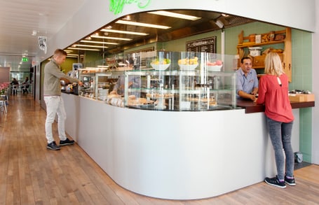 Cafeteria mit Theke und zwei Personen in Gesprächen.