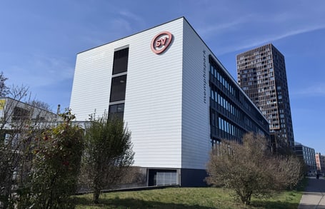 Bürogebäude mit SV-Logo, blauem Himmel, grüner Umgebung.