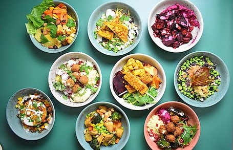 9 farbige Bowls mit Essen auf einem blauen Untergrund