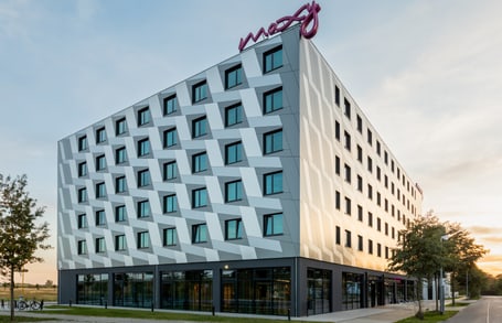 Moderne Hotelgebäude mit geometrischer Fassade bei Sonnenuntergang.