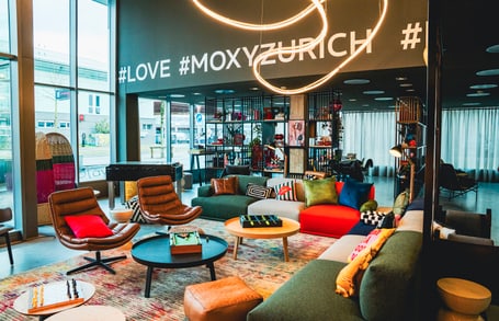 Moderne Hotellobby mit bunten Möbeln und Hashtags an der Wand.