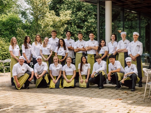 Gruppe von Menschen in Uniformen posiert draussen vor einem Gebäude.