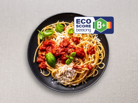 Teller mit Spaghetti und Tomatensosse, ECO-Score B+ Etikett.