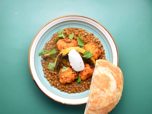 Linsengericht mit Brot auf grünem Hintergrund.