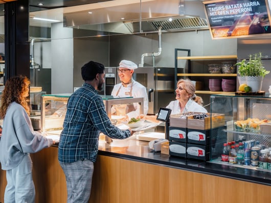 Menschen bestellen Essen an einem Imbissschalter.