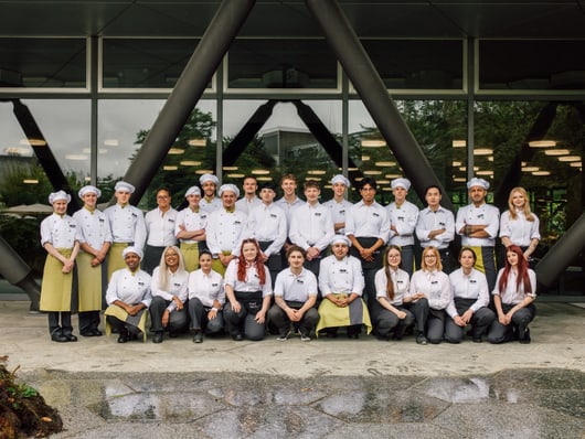 Gruppe von Menschen in Kochuniformen vor einem Gebäude.