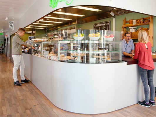 Cafeteria mit Theke und zwei Personen in Gesprächen.