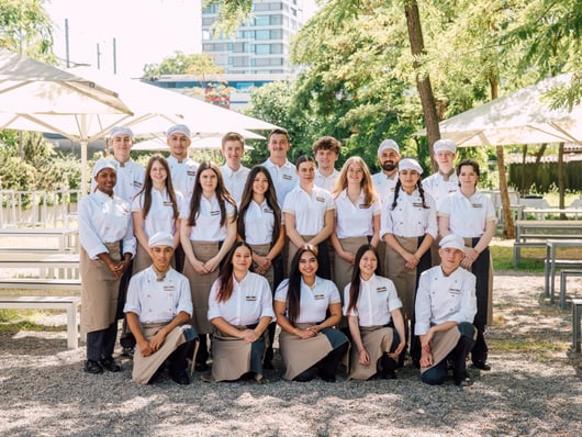 Gruppe von Menschen, die draussen in Uniformen posieren.