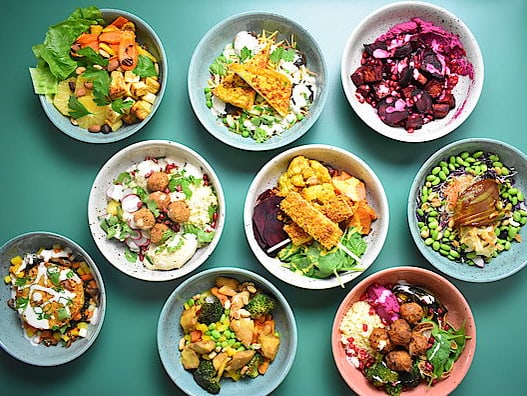9 farbige Bowls mit Essen auf einem blauen Untergrund