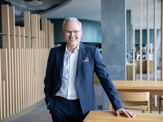 Lächelnder Mann in Anzug steht in modernem Restaurantbereich.