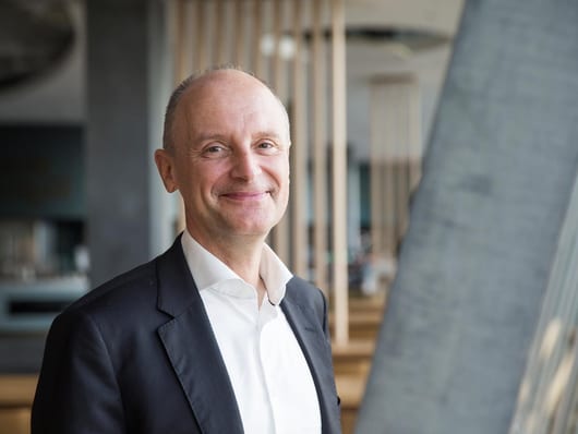 Pierre-Alain Graf Portrait bis zur Brust mit einem lachen. er trägt einen Anzug und hat keine Haare