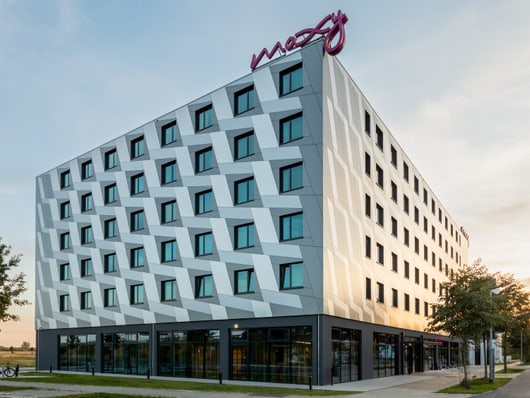 Moderne Hotelgebäude mit geometrischer Fassade bei Sonnenuntergang.