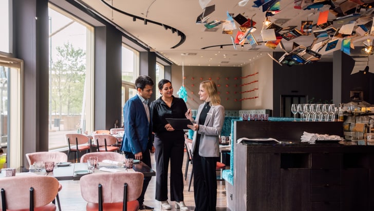 Drei Personen unterhalten sich in einem modernen Café mit Büchern an der Decke.