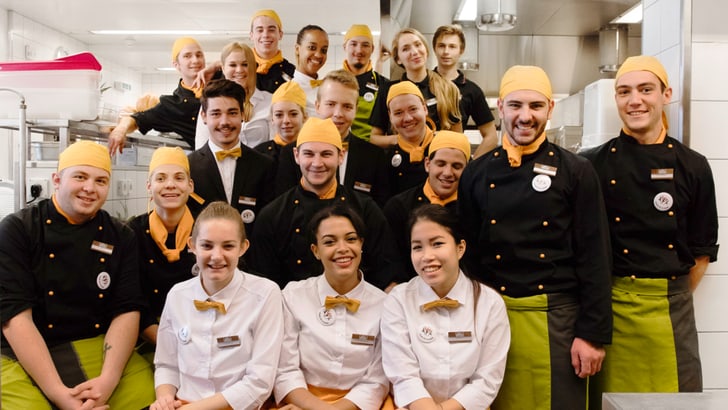 Gruppenfoto von Restaurantpersonal in Küchenumgebung.