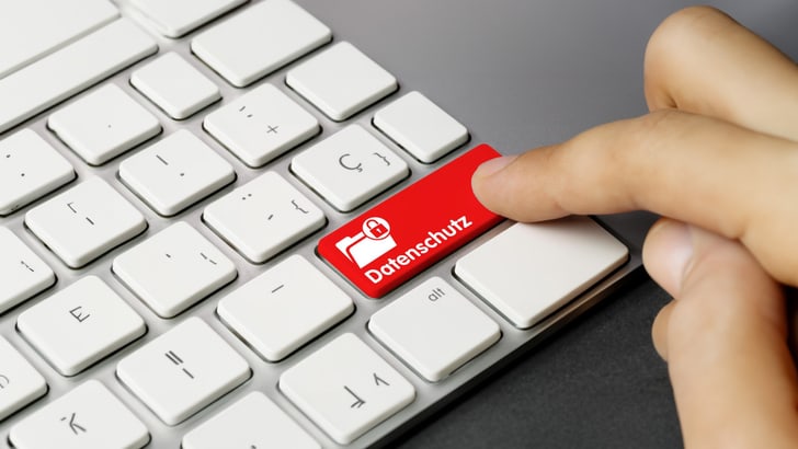 Finger drückt eine rote Taste mit der Aufschrift 'Datenschutz' auf einer Computertastatur.
