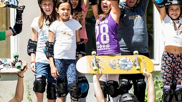 Gruppe von Kindern mit Helmen und Skateboards, die fröhlich posieren.