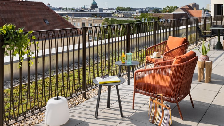 Terrasse mit zwei Stühlen, Tisch und Blick auf die Stadt.