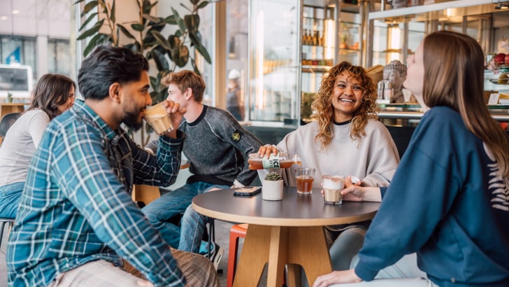 Junge Leute sitzen bei Kaffee und Gesprächen in einem Café.