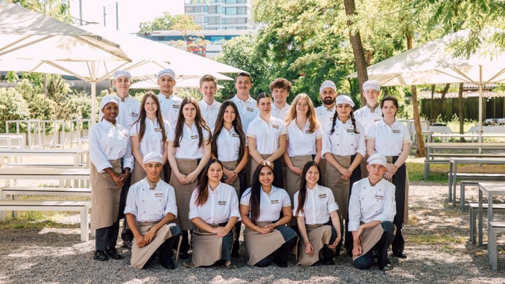 Gruppe von Menschen, die draussen in Uniformen posieren.