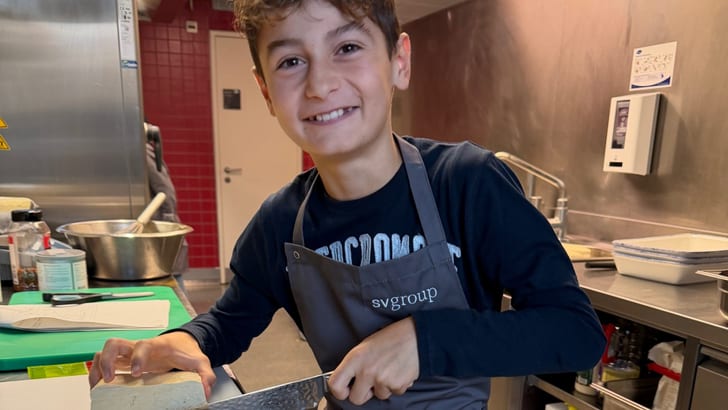 Junge schneidet Brot in einer Küche.