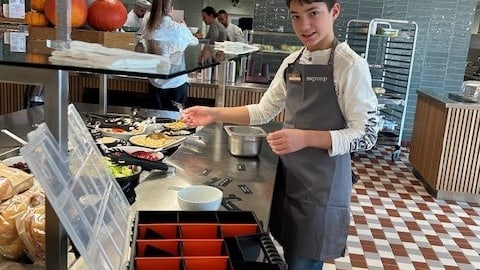 Junge kocht in moderner Küche, trägt Schürze.