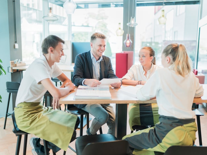 Gruppenbild Lernende mit Berufsbildner an einem Tisch