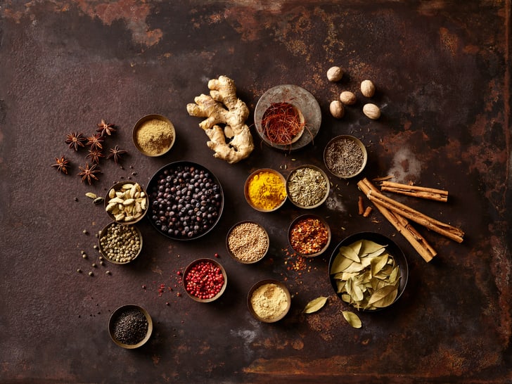 Verschiedene Gewürze auf braunem Hintergrund arrangiert.