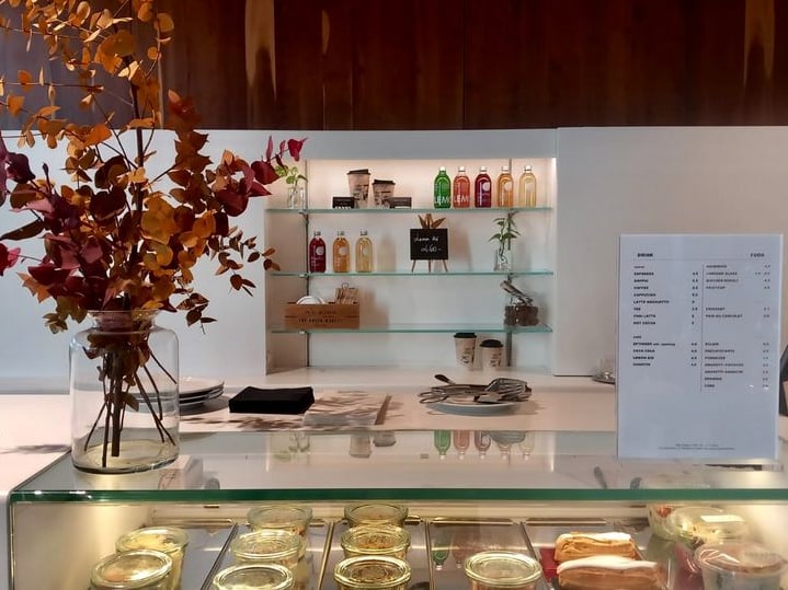 Café-Theke mit Getränken, Speisekarte und Blumenarrangement.