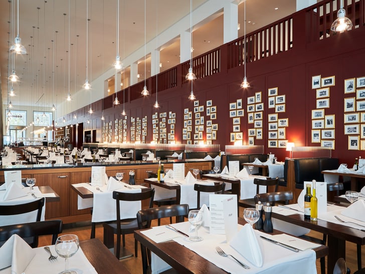 Elegantes Restaurant mit weiss gedeckten Tischen und Wandkunst.