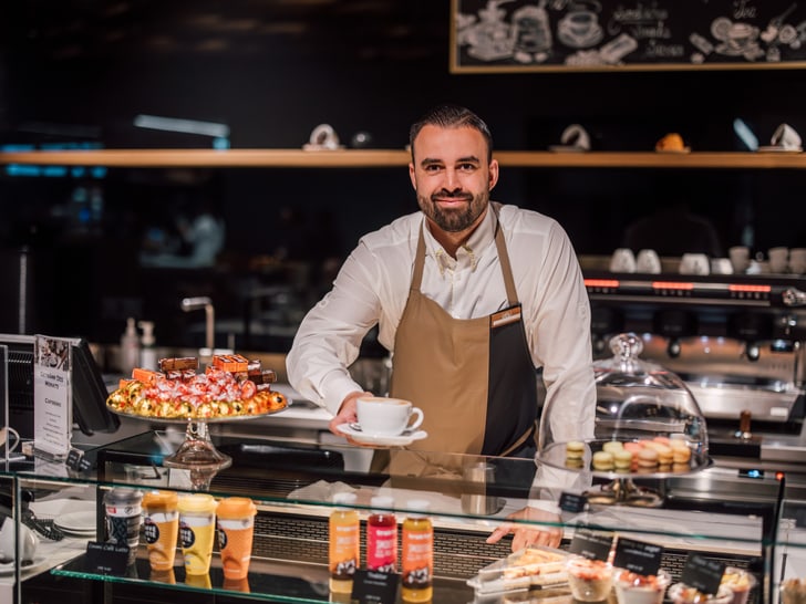 Barista bietet Kaffee an der Theke eines Cafés an.