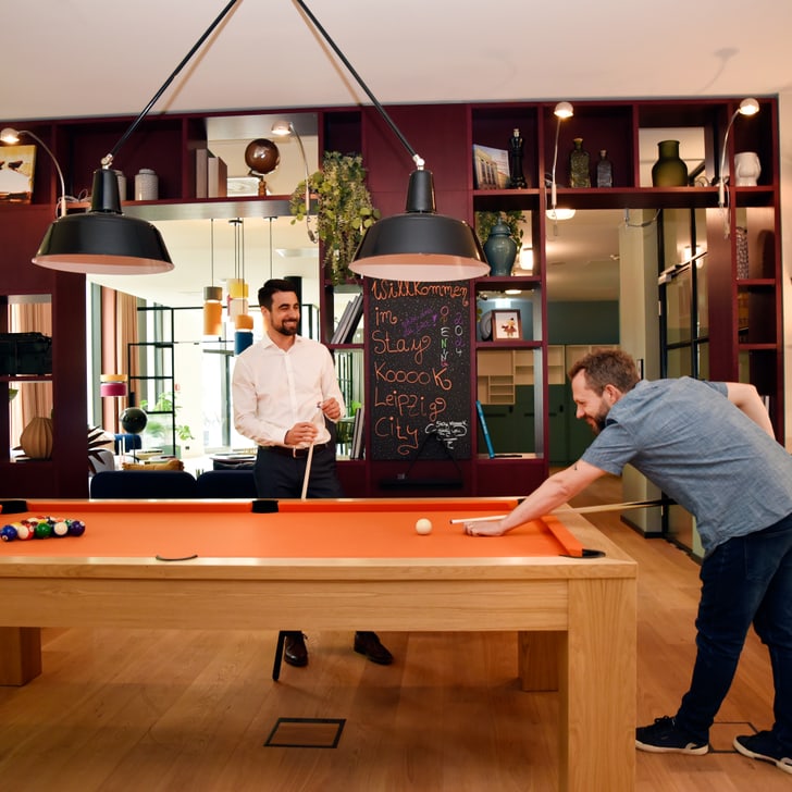 Zwei Männer spielen Billard in einem stilvollen Raum.