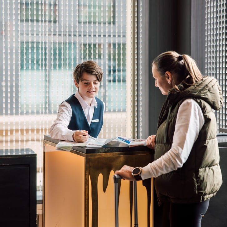 Rezeptionist hilft einer Frau an der Hotelrezeption.