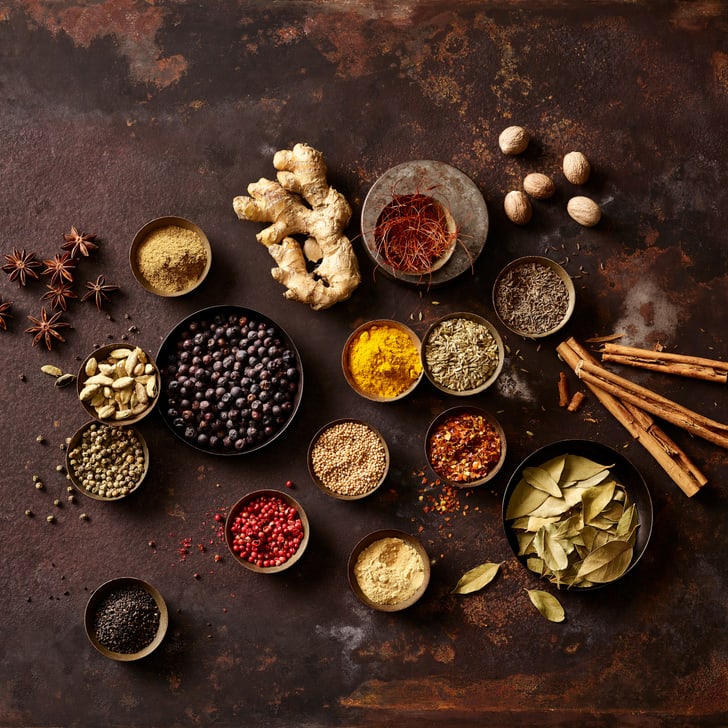 Verschiedene Gewürze auf braunem Hintergrund arrangiert.