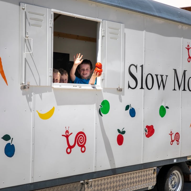 Zwei Personen winken aus dem Slow Mobil Fahrzeugfenster.