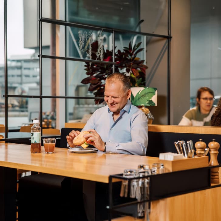 Mann isst Sandwich in modernem Café.
