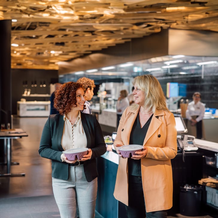 Zwei Frauen gehen in einem Restaurant mit moderner Inneneinrichtung.