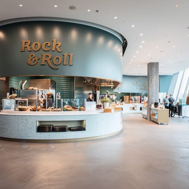 Moderne Cafeteria mit runden Theken und Personen in weisser Kleidung.