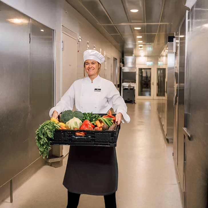 Koch in Küche mit Kiste voller Gemüse.