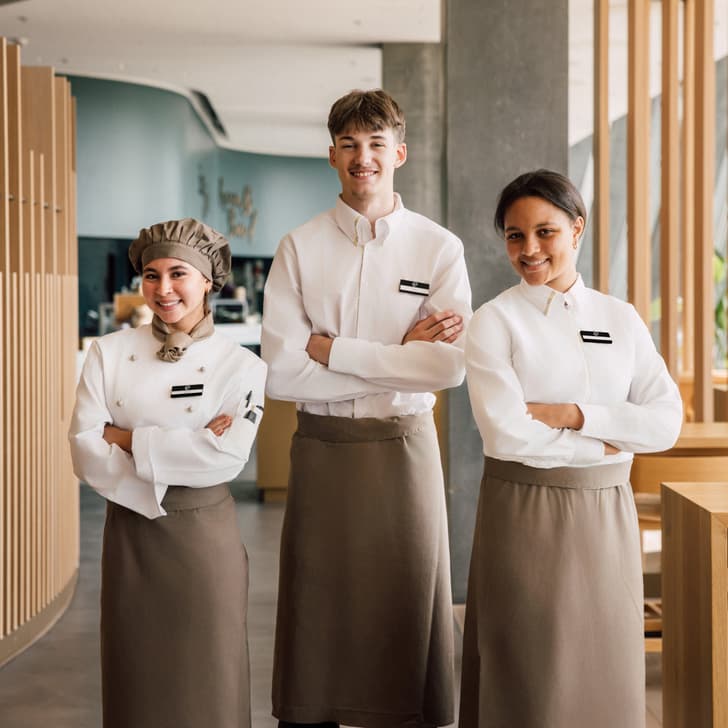 Drei Personen in Arbeitsuniformen stehen in einem modernen Restaurant.