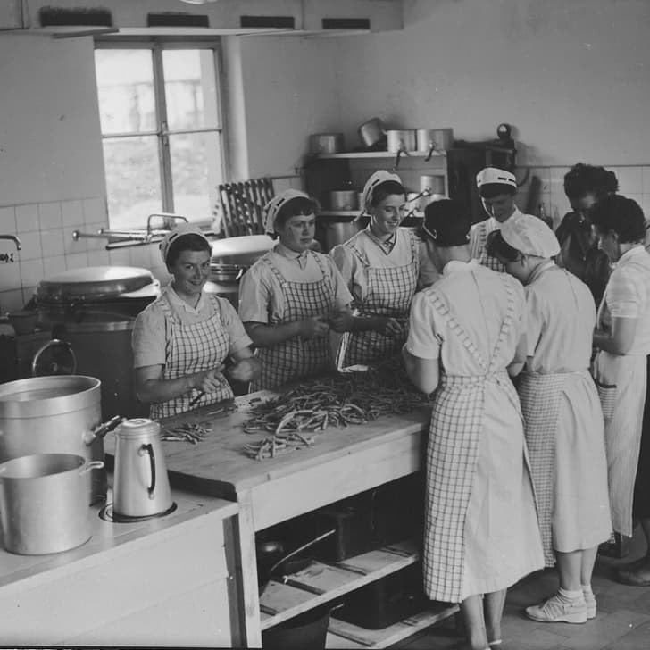 Historisches Bild von Frauen in der Küche, die Bohnen schneiden.