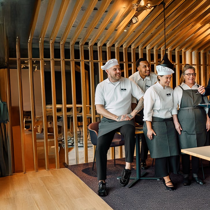 Gruppe von Restaurantmitarbeitern in Diskussion mit Management im Speisesaal.