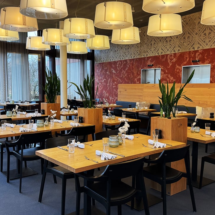 Leeres Restaurant mit Holztischen und Pflanzen, moderne Beleuchtung.