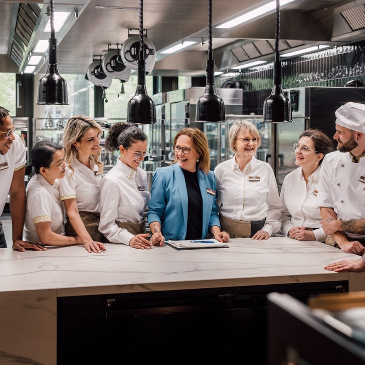 Team von Köchen und Angestellten versammelt sich in der modernen Küche.